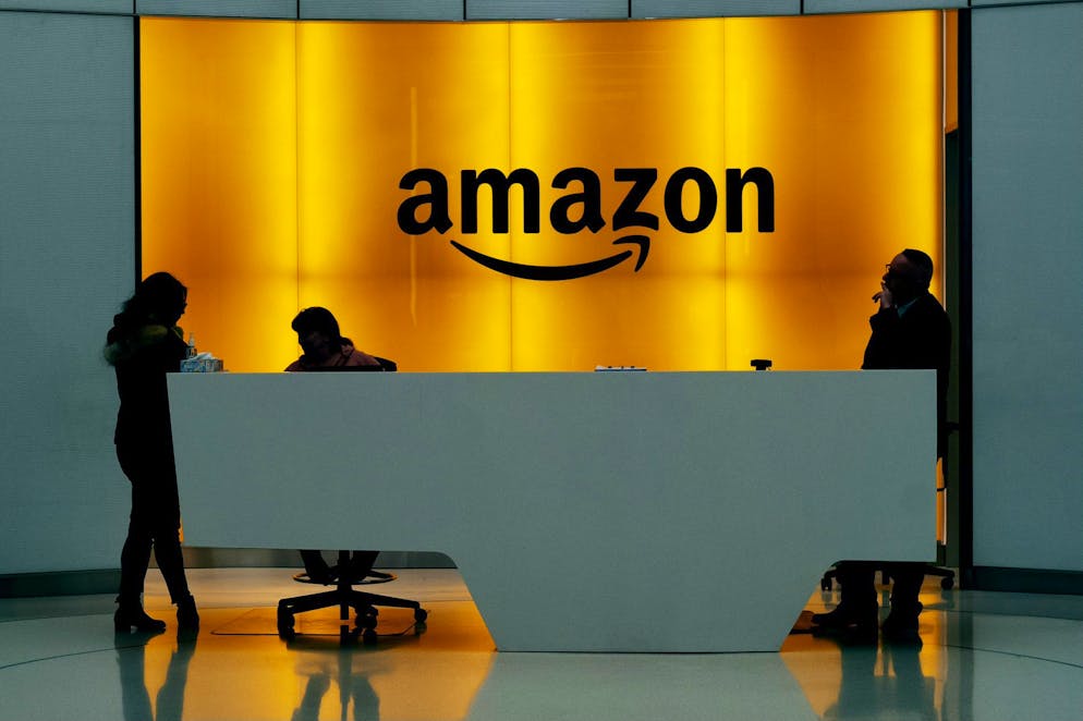 FILE - In this Feb. 14, 2019 file photo, people stand in the lobby for Amazon offices in New York. Amazon finally has its answer to ChatGPT. The tech giant said Tuesday, Nov. 28, 2023, it will launch Q – a generative-AI powered chatbot for businesses. (AP Photo/Mark Lennihan, File)