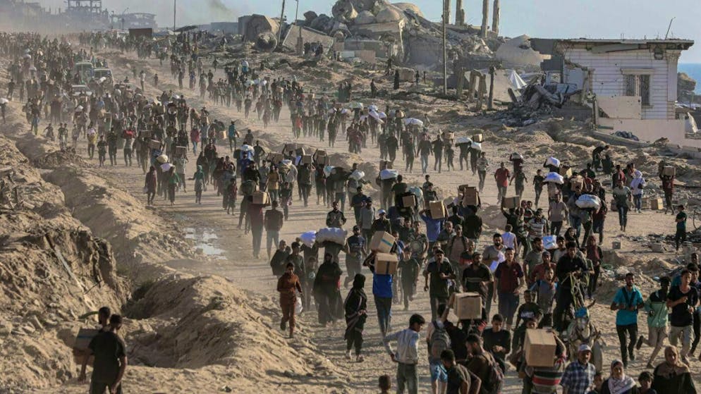 Palestinians carry food parcels distributed by The Gaza Humanitarian Foundation (GHF). (archive picture)