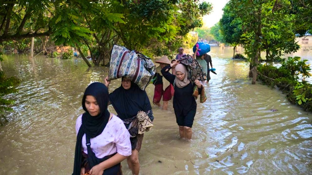 dpatopbilder - People carry their belongings as they wade through the water in a flooded village. Photo: Reza Saifullah/AP/dpa