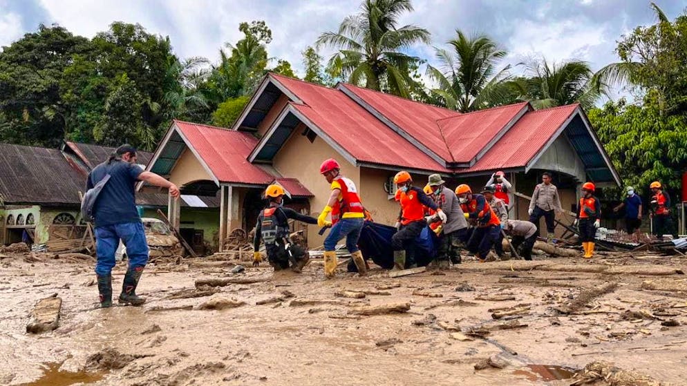 Rescue workers carry the body of a flood victim. Photo: Ade Yuandha/AP/dpa