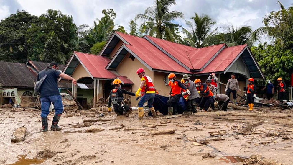 Rettungskräfte tragen die Leiche eines Flutopfers. Foto: Ade Yuandha/AP/dpa