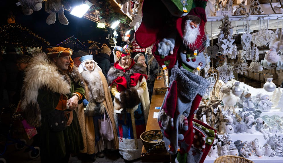 Surtourisme. (ARCHIVES) Des personnes vêtues de costumes médiévaux admirent des décorations de Noël sur un stand du marché de Noël de Strasbourg, dans l'est de la France, le 12 décembre 2024. Kaysersberg et Riquewihr comptent parmi les villages touristiques les plus populaires, près de 4 millions de personnes ayant visité les marchés de Noël de la région du Haut-Rhin l'année dernière. (Photo de SEBASTIEN BOZON / AFP)