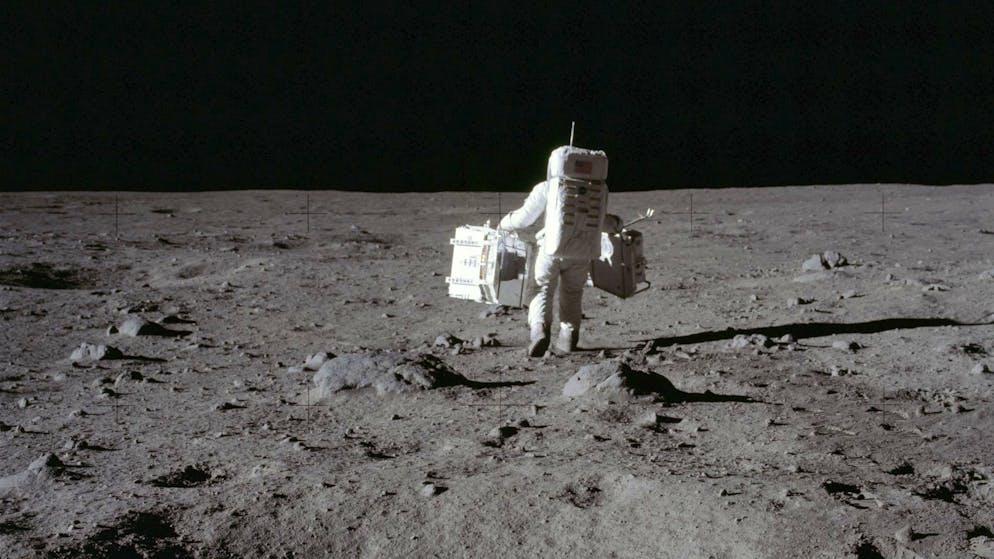 Im Juli 1969 trägt Astronaut Buzz Aldrin ein Paket mit seismischen Experimenten und den Laser-Entfernungsmesser zum Einsatzort auf der Mondoberfläche.