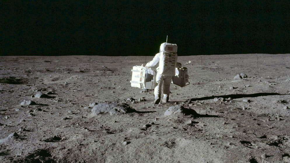 In July 1969, astronaut Buzz Aldrin carries a package containing seismic experiments and the laser range finder to the deployment site on the surface of the moon.