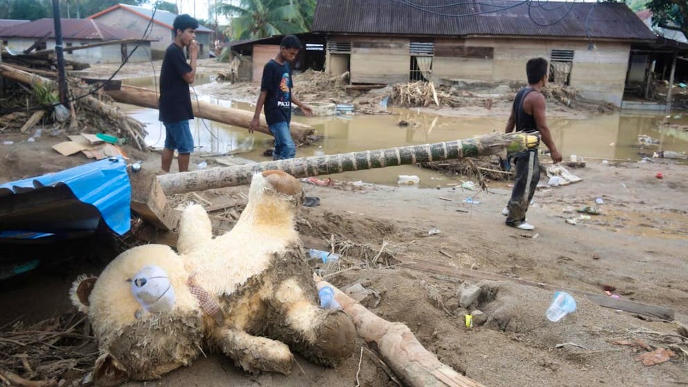 dpatopbilder - Menschen gehen durch ein von einer Sturzflut betroffenen Dorf in Nordsumatra. Foto: Binsar Bakkara/AP/dpa