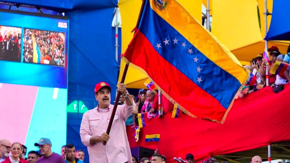 Venezuelan President Nicolas Maduro waves a Venezuelan flag during a swearing-in ceremony for government-organized community committees at the presidential palace. Photo: Ariana Cubillos/AP/dpa