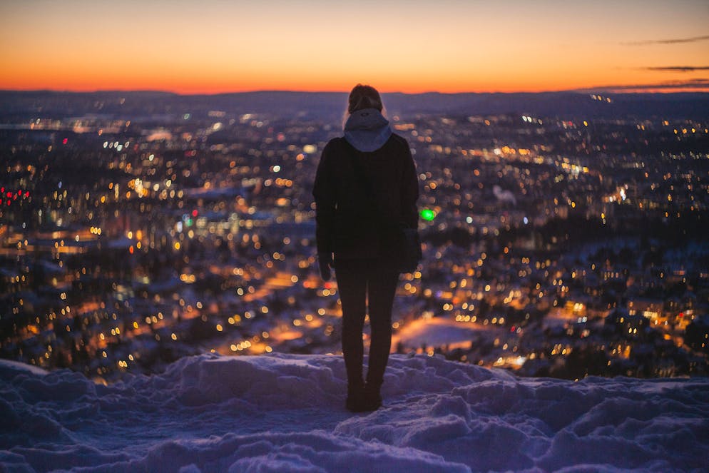 Eine Frau blickt auf das schneebedeckte Oslo. 
