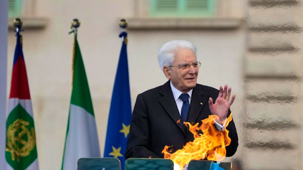 Il presidente italiano Sergio Mattarella vicino alla fiamma olimpica.
