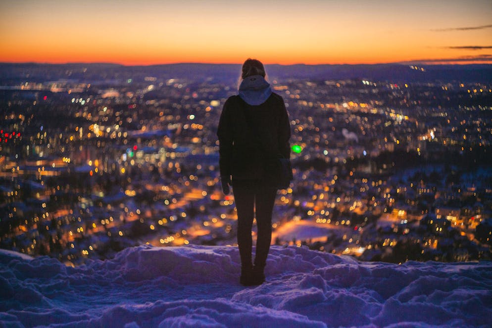 Una donna guarda Oslo innevata. 