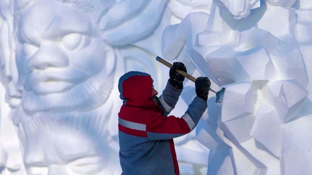 ARCHIV - Ein Künstler arbeitet an einer Schneeskulptur in Harbin (Archivbild). Foto: Andy Wong/AP/dpa