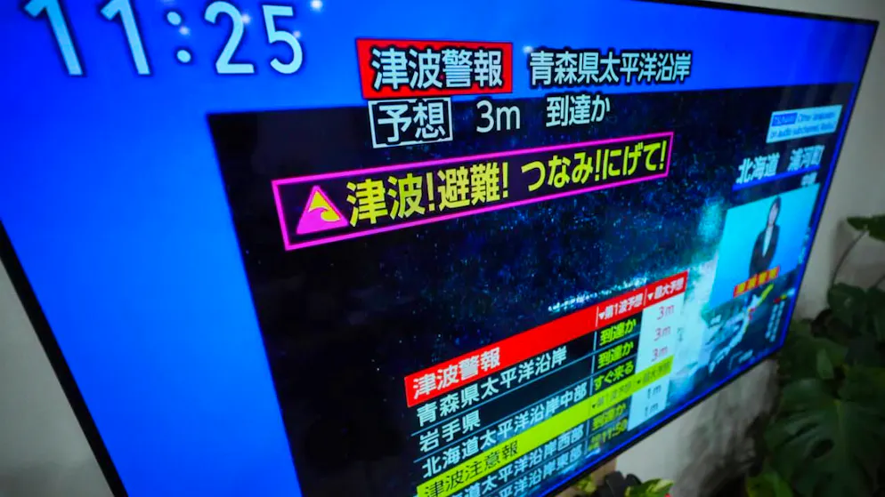 dpatopbilder - Eine Tsunami-Warnung wird auf einem Fernseher in Yokohama, in der Nähe von Tokio, angezeigt. Nach einem starken Erdbeben vor der japanischen Nordküste wurde eine Tsunami-Warnung ausgegeben. Foto: Eugene Hoshiko/AP/dpa