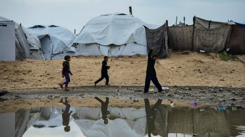 Vertriebene palästinensische Kinder laufen nach einem Unwetter durch ein Zeltlager in Gaza-Stadt. Foto: Jehad Alshrafi/AP/dpa