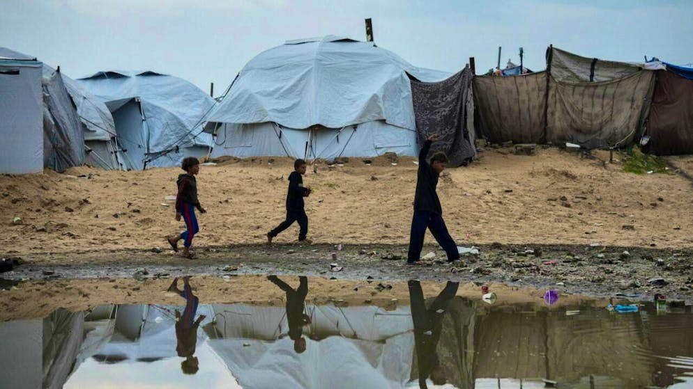 Displaced Palestinian children walk through a tent camp in Gaza City after a thunderstorm. Photo: Jehad Alshrafi/AP/dpa