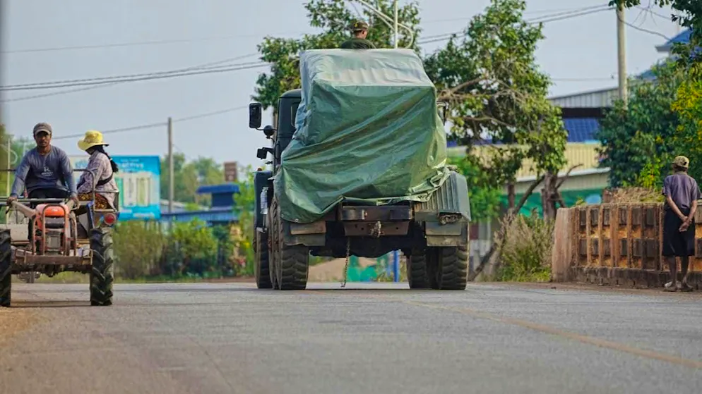 A Cambodian military vehicle drives past a tractor full of evacuees in Srey Snam in Siem Reap province. Thousands are on the run.