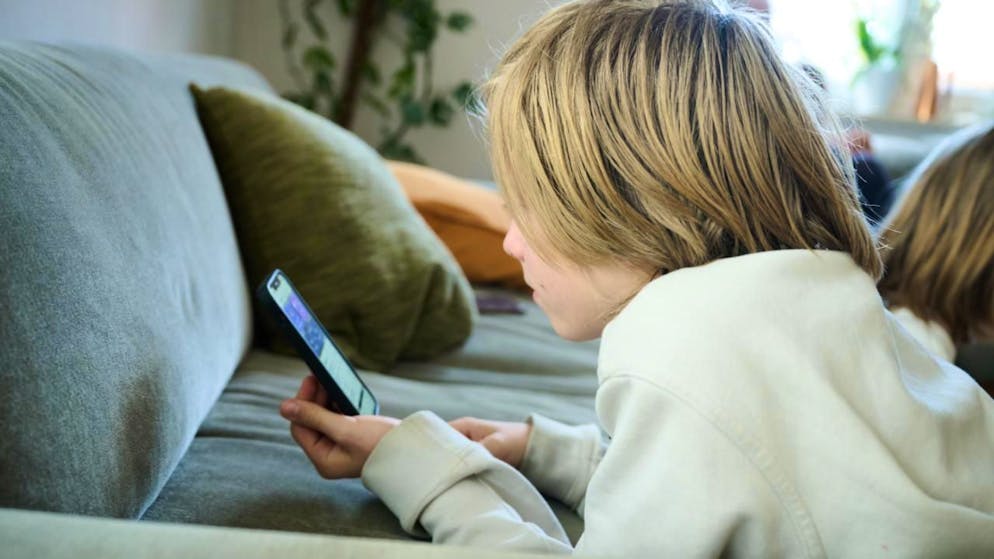 ARCHIV - ILLUSTRATION - Ein Junge liegt auf einem Sofa und guckt auf sein Smartphone. (gestellte Szene). Australien hat ein Social-Media-Verbot für Kinder und Jugendliche unter 16 Jahren eingeführt und ist damit weltweiter Vorreiter. Foto: Annette Riedl/dpa