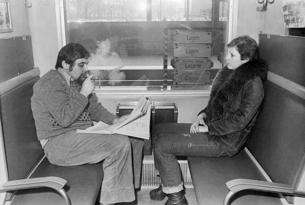 20 years of the smoking ban on SBB trains. In the wild 70s, smoke was a must in the compartment: Two train passengers in an SBB smoking compartment at Zurich main station, taken on February 19, 1976.