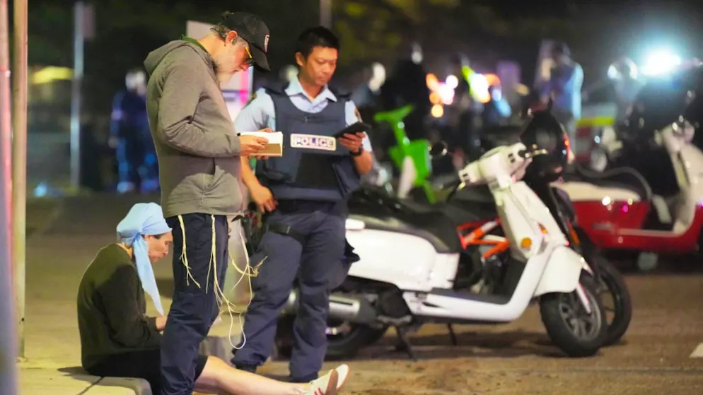 Des passants restent sur place tandis que la police établit un périmètre de sécurité à Bondi Beach après une fusillade signalée à Sydney, dimanche.