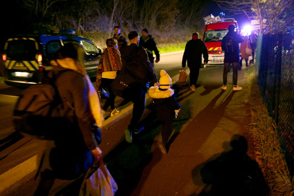 Des habitants évacuent les lieux d'une explosion dans un immeuble résidentiel à Trévoux, près de Lyon, qui a fait au moins quatre blessés et deux enfants morts, le 15 décembre 2025. (Photo par Alex MARTIN / AFP)