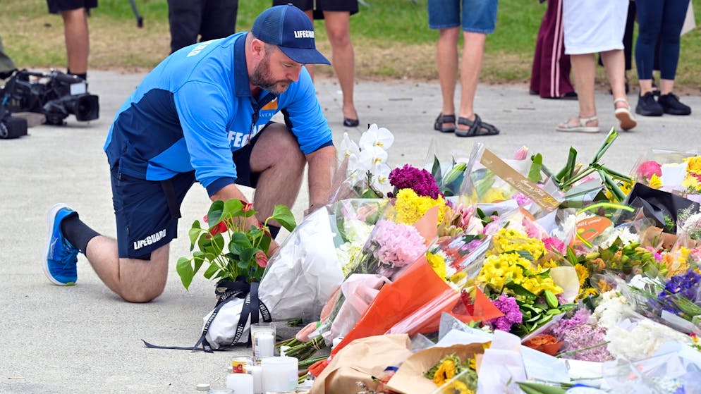 Ein Rettungsschwimmer legt Blumen am Bondi Beach nieder. (16. Dezember 2025)