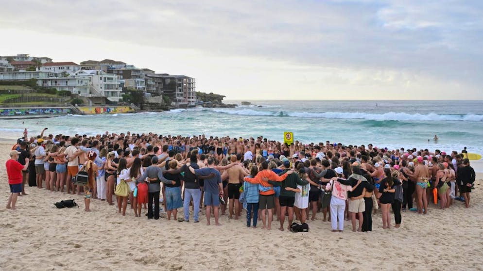 Schwimmer versammeln sich zu einer Mahnwache am Strand, um der Opfer des Anschlags am Bondi Beach zu gedenken. Foto: Mick Tsikas/AAP via AP/dpa