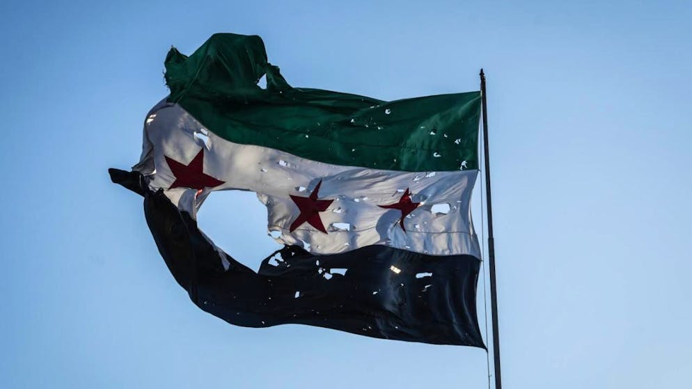 ARCHIV - Eine zerfetzte syrische Flagge weht vor dem syrischen Generalstabshauptquartier. Foto: Moawia Atrash/dpa/Symbolbild