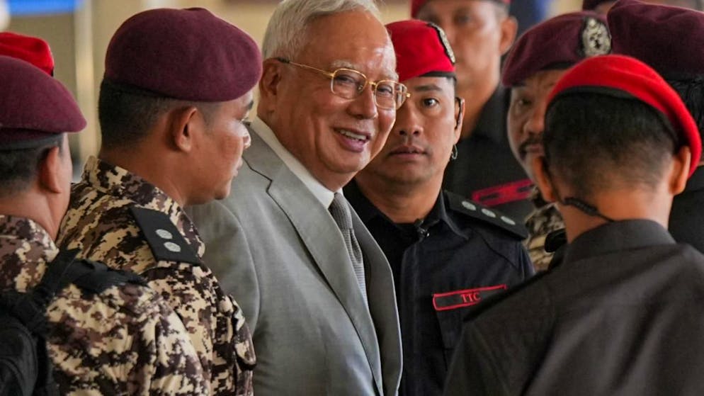 Der ehemalige malaysische Premierminister Najib Razak, Mitte, wird bei seiner Ankunft im Kuala Lumpur High Court Complex von Gefängnisbeamten eskortiert. Foto: Azneal Ishak/AP/dpa
