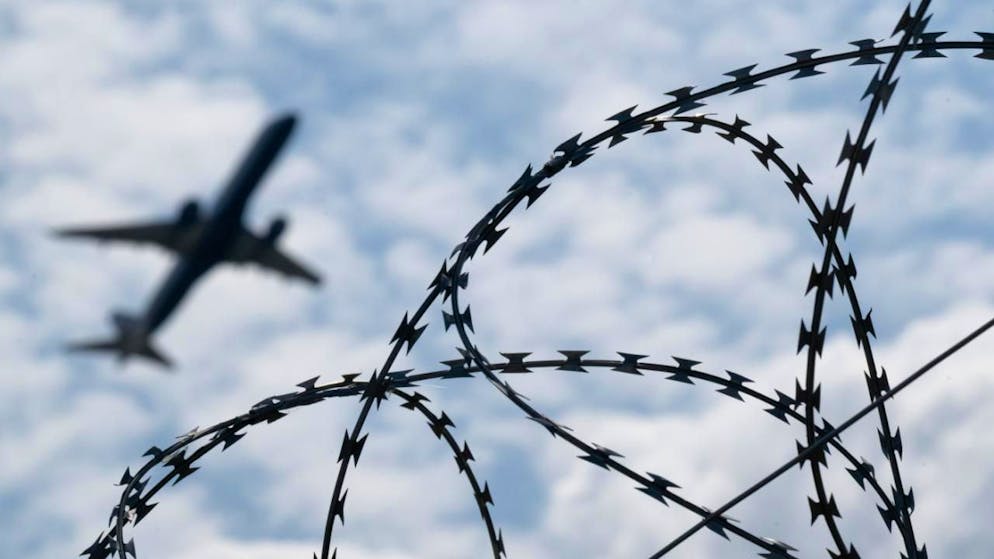 ARCHIV - Ein Flugzeug hebt am Flughafen BER hinter einem Zaun mit Natodraht ab. Foto: Sebastian Gollnow/dpa