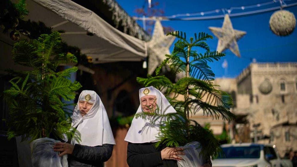 ARCHIVE - Orthodox Christian women carry their Christmas trees home before Christmas. Photo: Leo Correa/AP/dpa