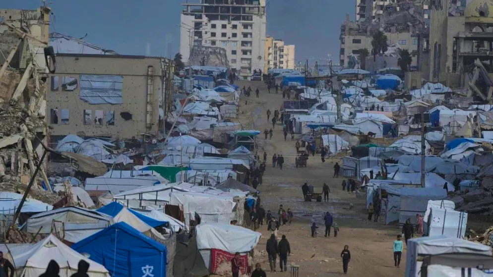 dpatopbilder - Palestinians walk in the rain along a street with destroyed buildings. Photo: Jehad Alshrafi/AP/dpa