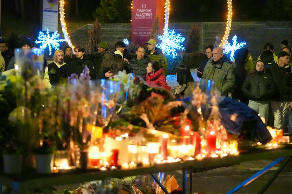People gather in front of "Le Constellation" in Crans-Montana. They light candles and lay flowers.