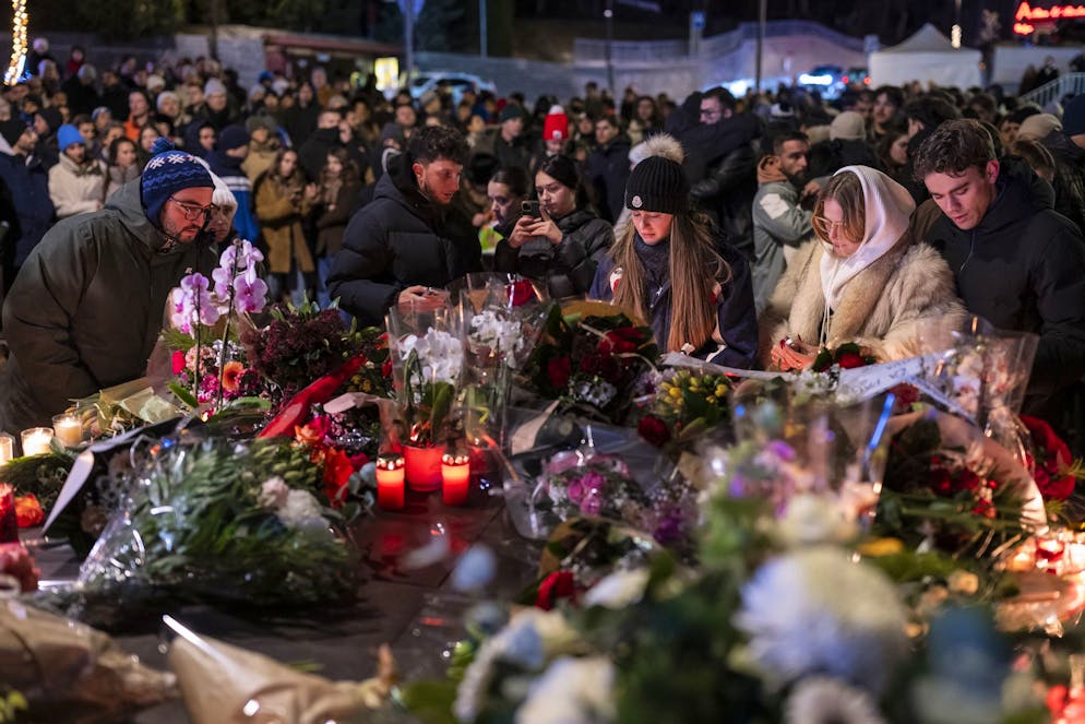 Des personnes en deuil ont déposé fleurs et bougies sur une table dressée à l'entrée de la route menant au bar, masqué par des bâches blanches. Deux policiers montaient la garde devant le périmètre de sécurité.