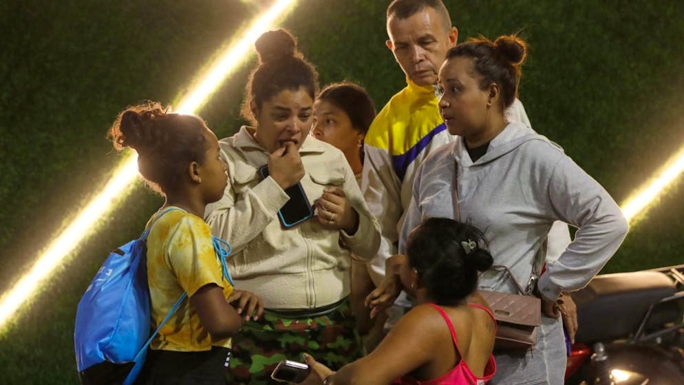 Anwohner aus einem Gebäude, das evakuiert wurde, stehen in der Nähe des Präsidentenpalastes Miraflores, nachdem Explosionen und tieffliegende Flugzeuge in Caracas, Venezuela, am Samstag, 3. Januar 2026, zu hören waren. Foto: Cristian Hernandez/AP/dpa