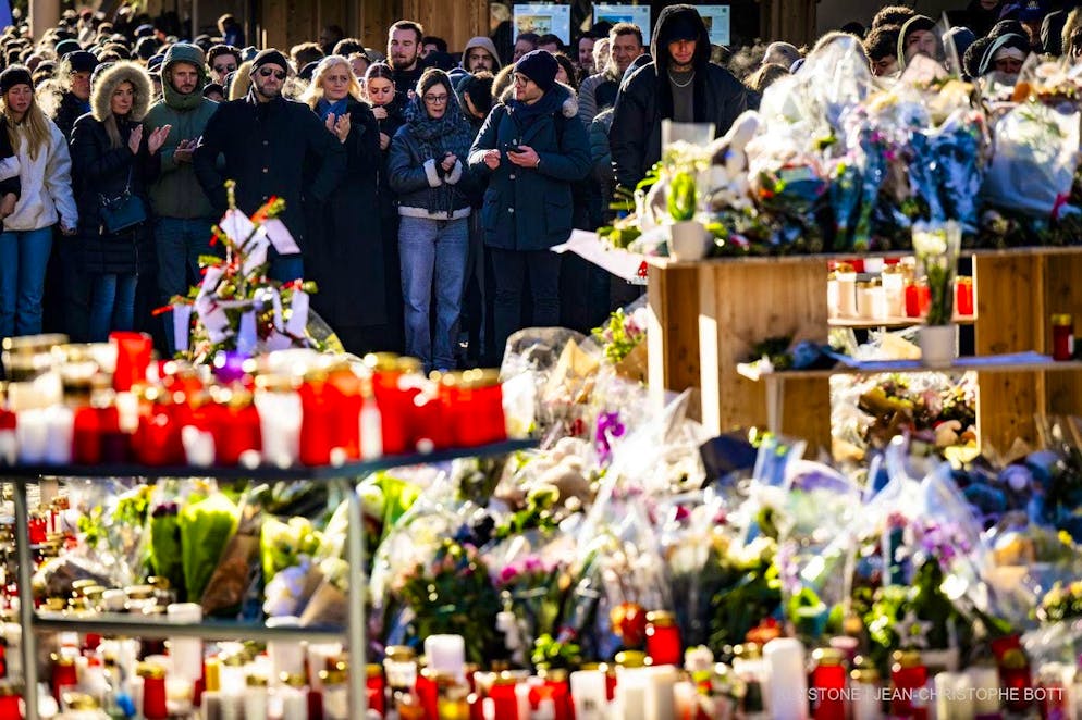 Mourners gather around flowers and candles to remember the victims of the fire at the "Le Constellation" bar and lounge in Crans-Montana, Switzerland, on Sunday, January 4, 2026.