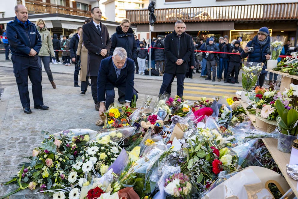 Le conseiller fédéral Beat Jans, au centre déposant des fleurs en hommage aux victimes après avoir inspecté le site de l'incendie du « Le Constellation ».