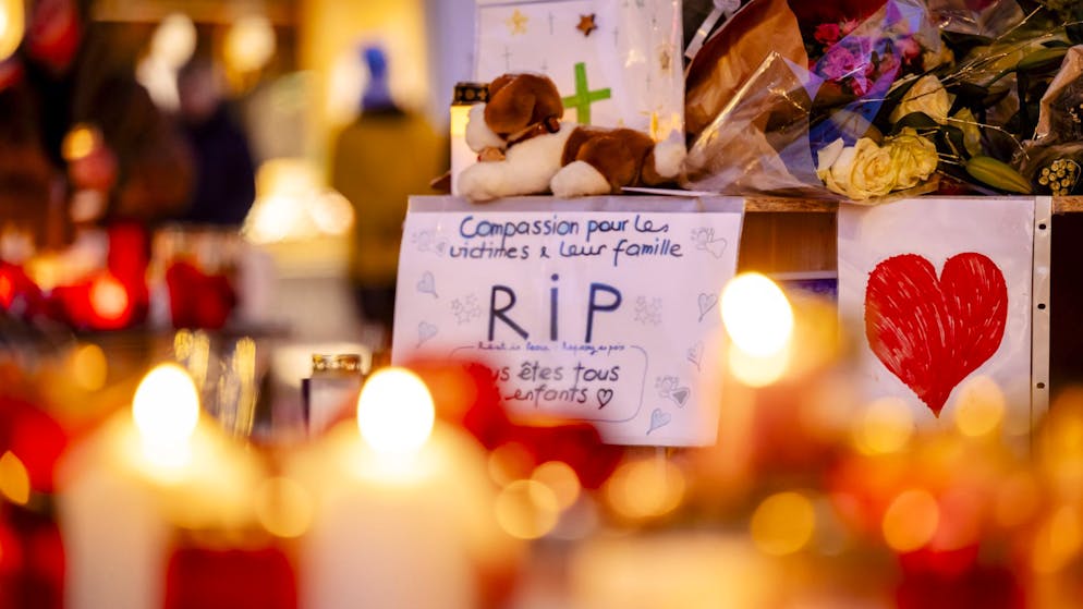 Menschen haben Blumen, Kerzen und Karten  in Crans-Montana niedergelegt.