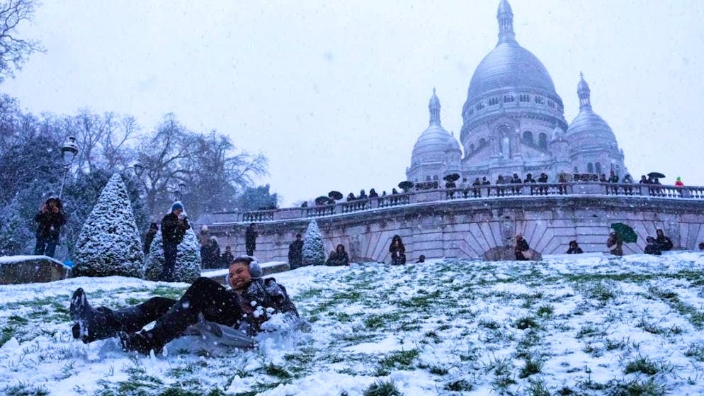 dpatopbilder - People having fun in the snow on a slope near the Sacre-Coeur Basilica in Paris. Photo: Aurelien Morissard/AP/dpa