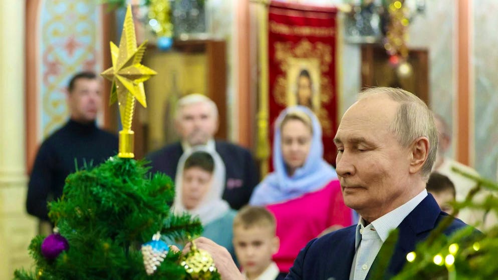 Russian President Vladimir Putin (r.) at a Christmas service in a church in Moscow.