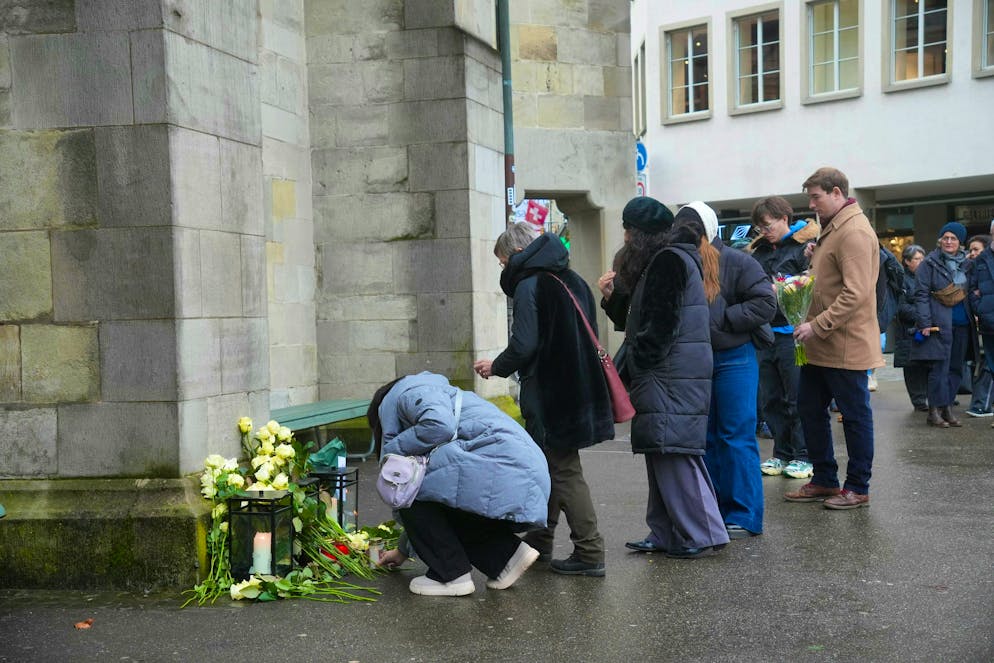 Numerous people lay flowers in front of the Fraumünster. 