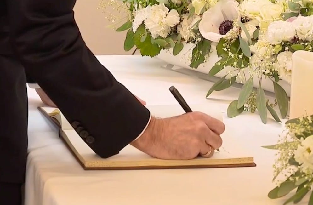 Emmanuel Macron schreibt in das Kondolenzbuch. 