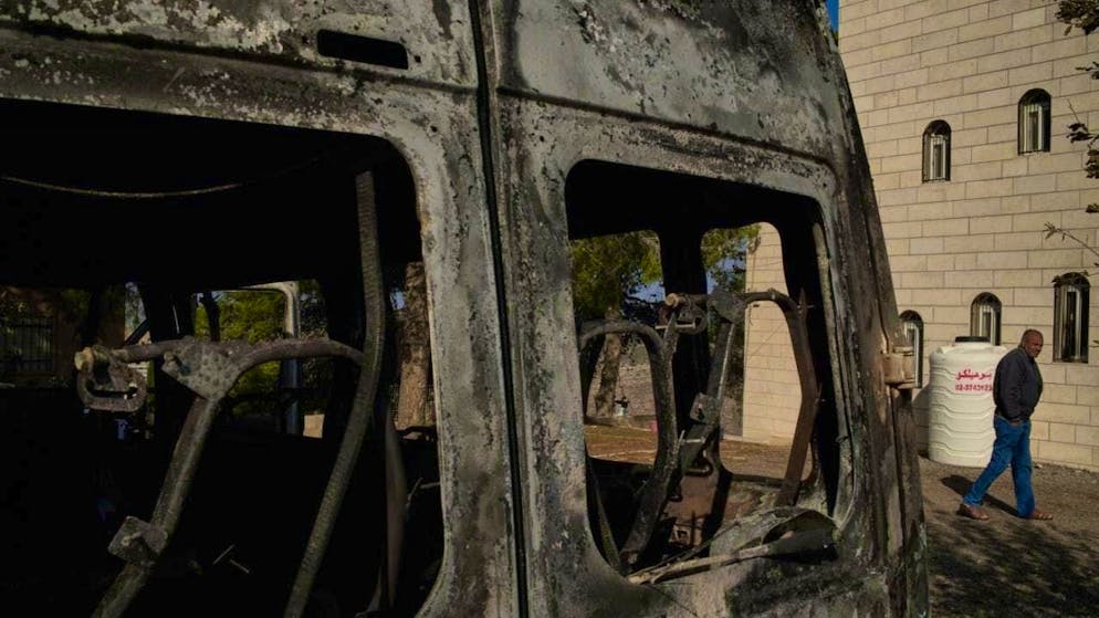 ARCHIVE - Moussab Mshala walks past a vehicle burnt in an attack by Israeli settlers outside his home in the West Bank village of al-Jab'a, near Bethlehem. Photo: Leo Correa/AP/dpa