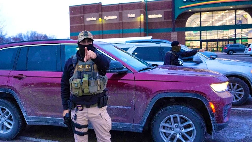 An ICE officer warns a photographer to stay behind while a person is detained. Photo: Adam Gray/AP/dpa