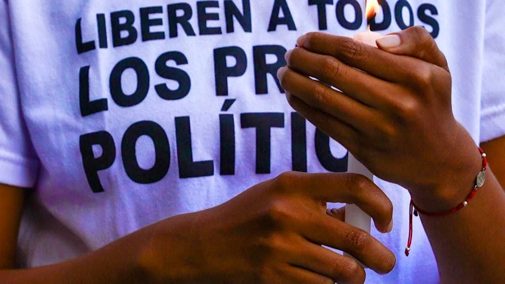 A woman holds a candle during a demonstration for the release of political prisoners near El Helicoide prison. Photo: Javier Campos/dpa