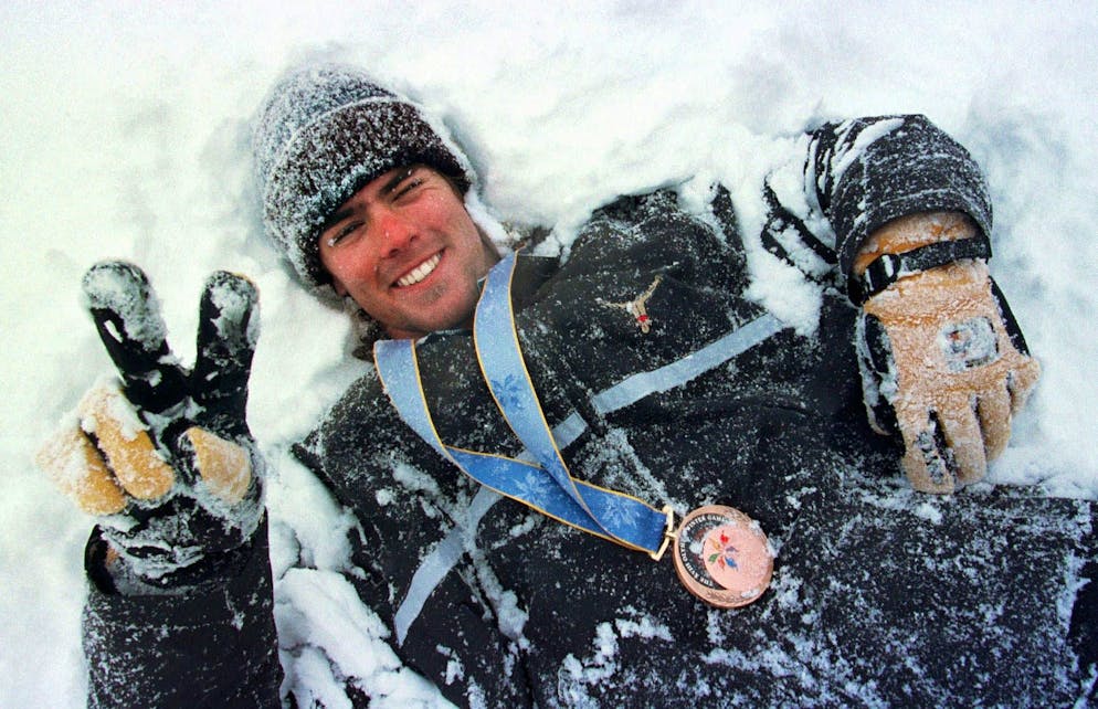 Der Schweizer Snowboarder Ueli Kestenholz wälzt sich 1998 geschmückt mit der Olympia-Bronzemedaille im Schnee von Nagano.