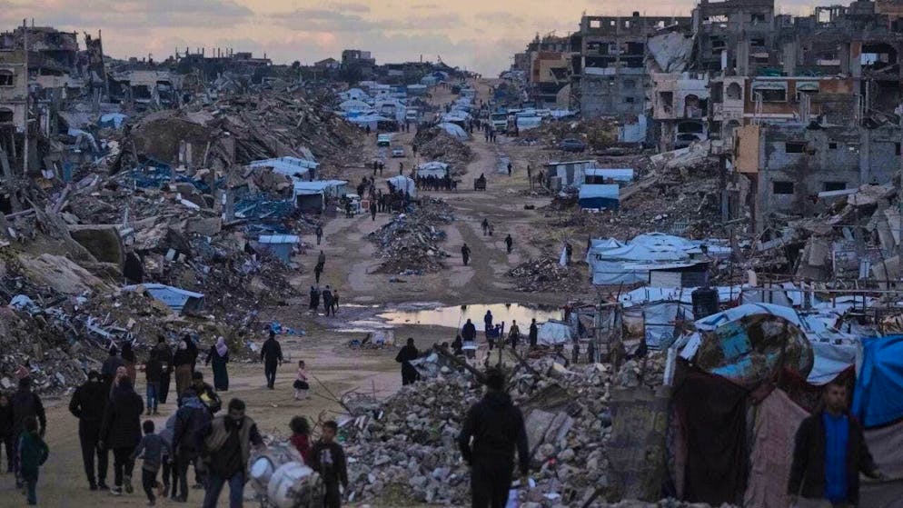 ARCHIVE - Palestinians walk past destroyed buildings in the northern Gaza Strip. Photo: Jehad Alshrafi/AP/dpa/Archive photo