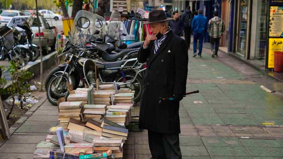 dpatopbilder - A man looks at books for sale on a sidewalk in downtown Tehran. Photo: Vahid Salemi/AP/dpa