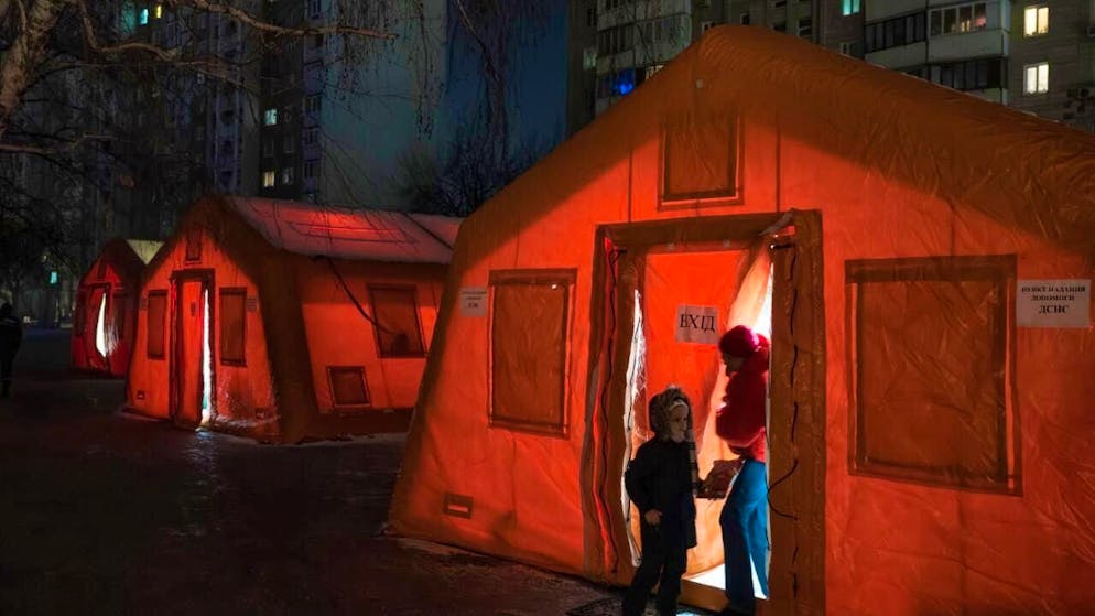 dpatopbilder - People stand at the entrance of a tent set up in a residential area where they can warm up after Russian airstrikes repeatedly hit the country's energy infrastructure. Photo: Vladyslav Musiienko/AP/dpa