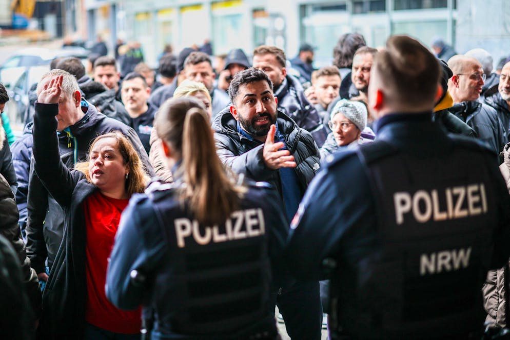 Aufgebrachte Kunden diskutieren vor der Sparkassenfiliale mit Polizeibeamten.