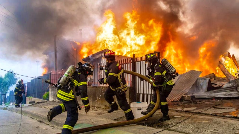 Firefighters fight a fire in a house as forest fires blaze. Photo: Javier Torres/AP/dpa