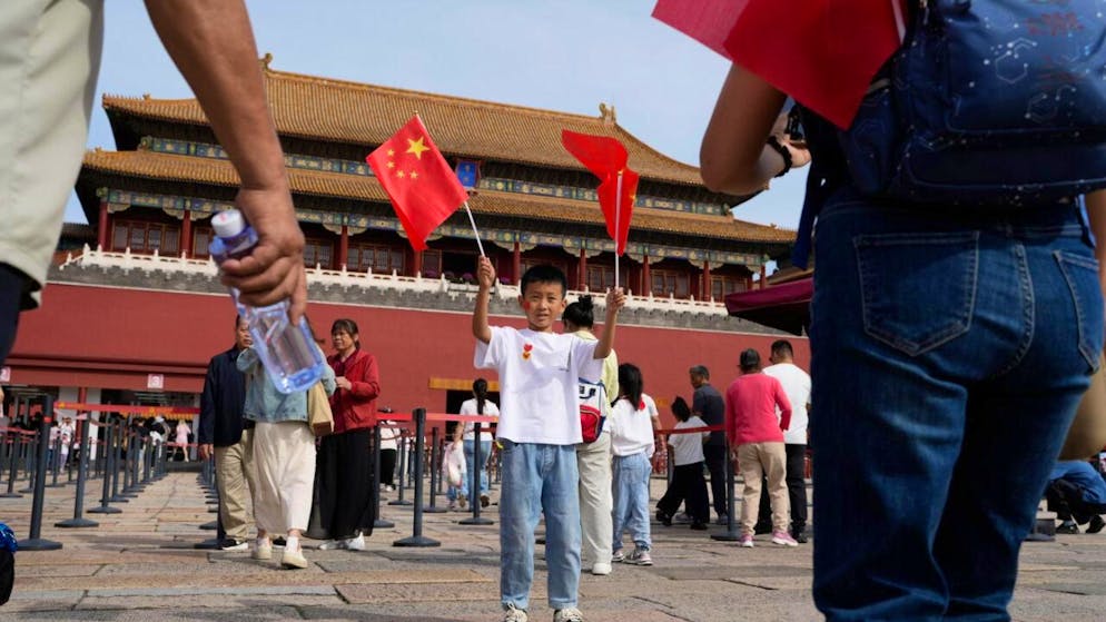ARCHIV - Ein Kind posiert für Fotos mit chinesischen Nationalflaggen vor der Verbotenen Stadt während des Nationalfeiertags. Foto: Ng Han Guan/AP/dpa