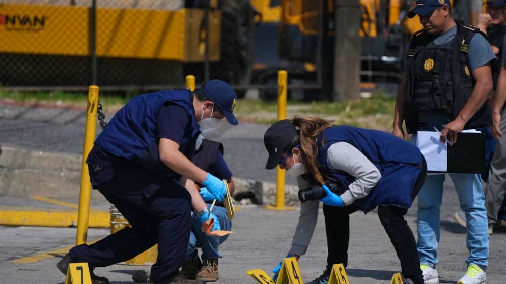 Des enquêteurs médico-légaux placent des marqueurs de preuves sur les lieux où les deux policiers ont été tués lors d’attaques survenues dans une prison abritant des chefs de gangs, à Villanueva, en périphérie de Guatemala City.
